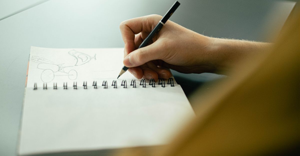 Niño dibujando ideas en una libreta junto a adultos