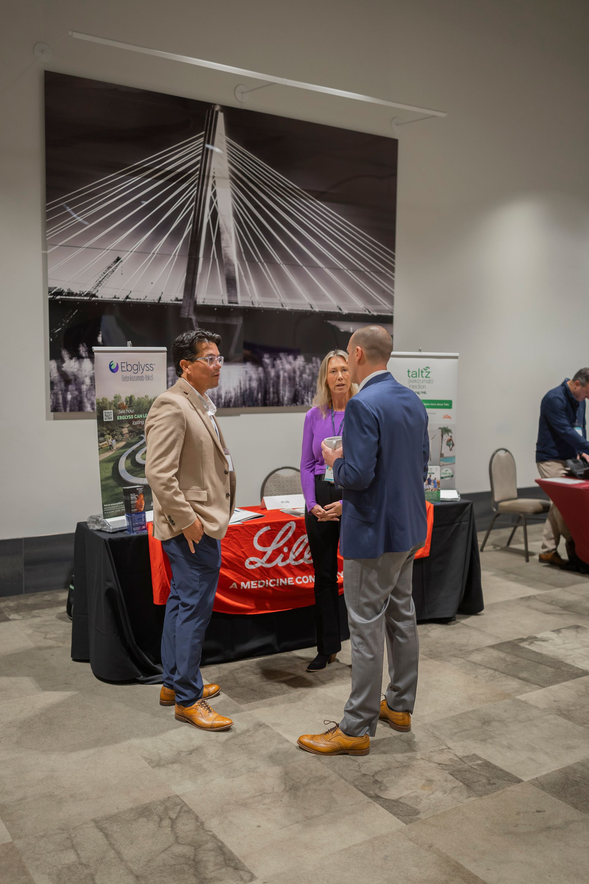 Two men talking at a booth with a red Budweiser banner in a conference hall