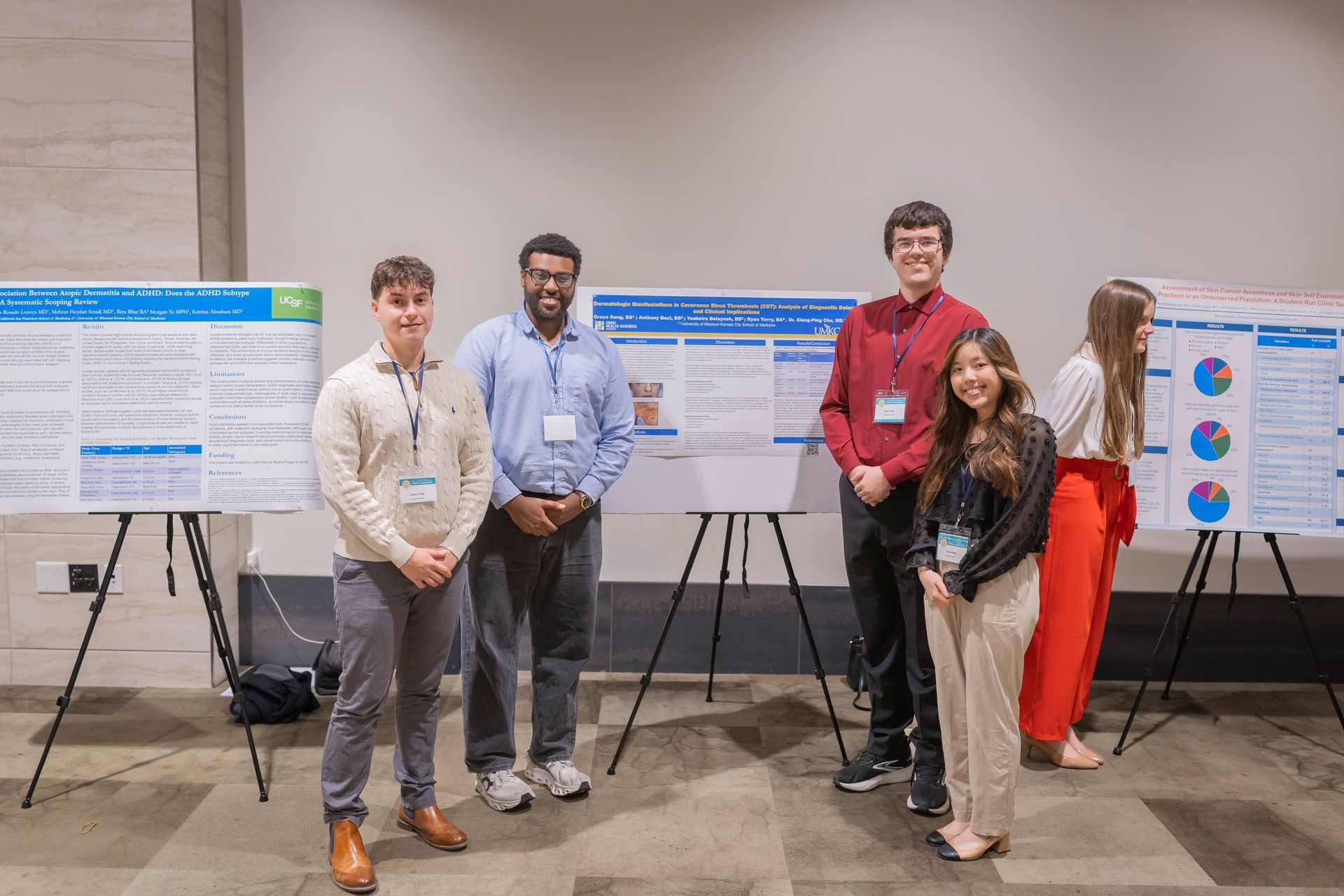Four people posing in front of poster boards at a conference presentation booth