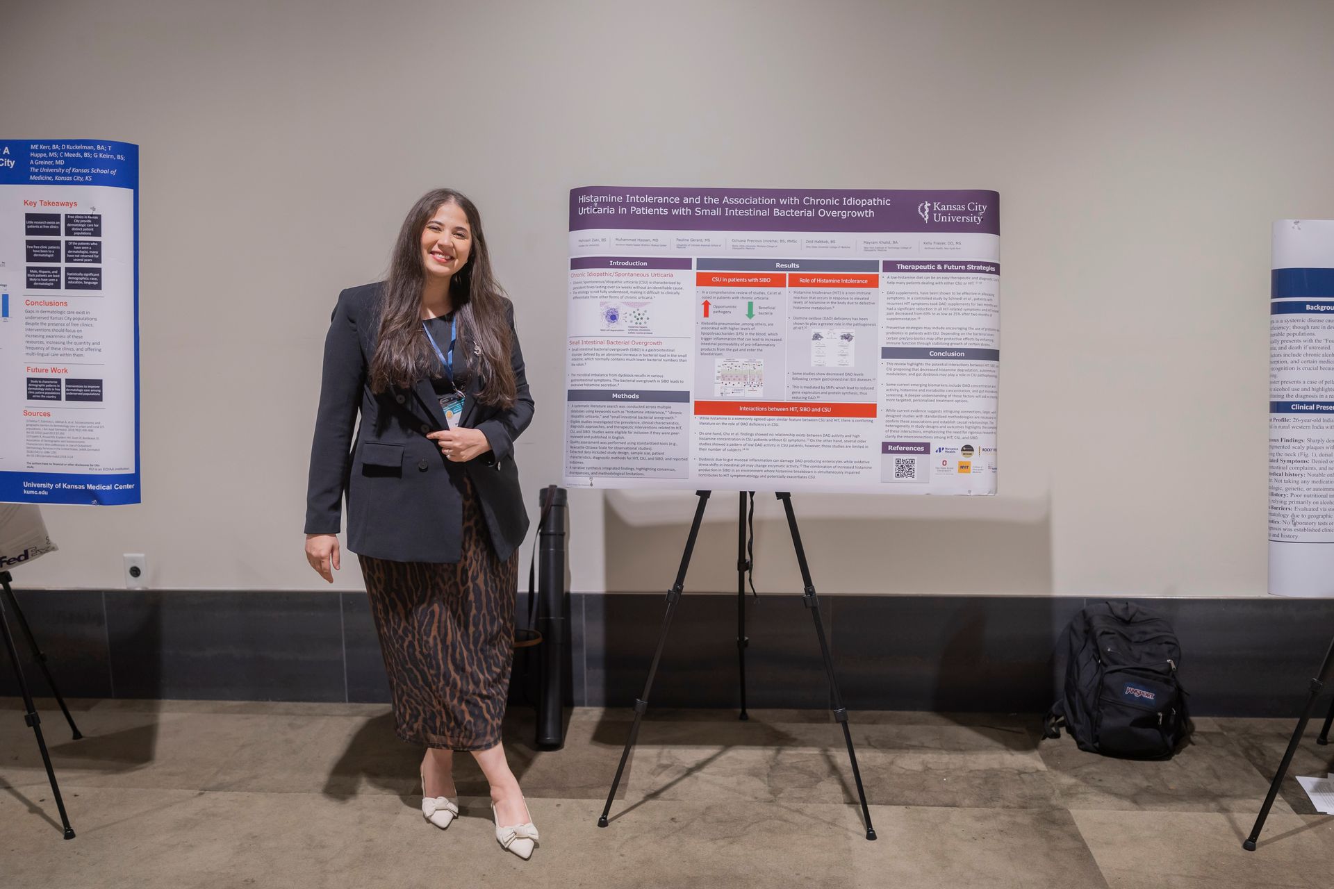 Woman standing beside a research poster on an easel in a conference room