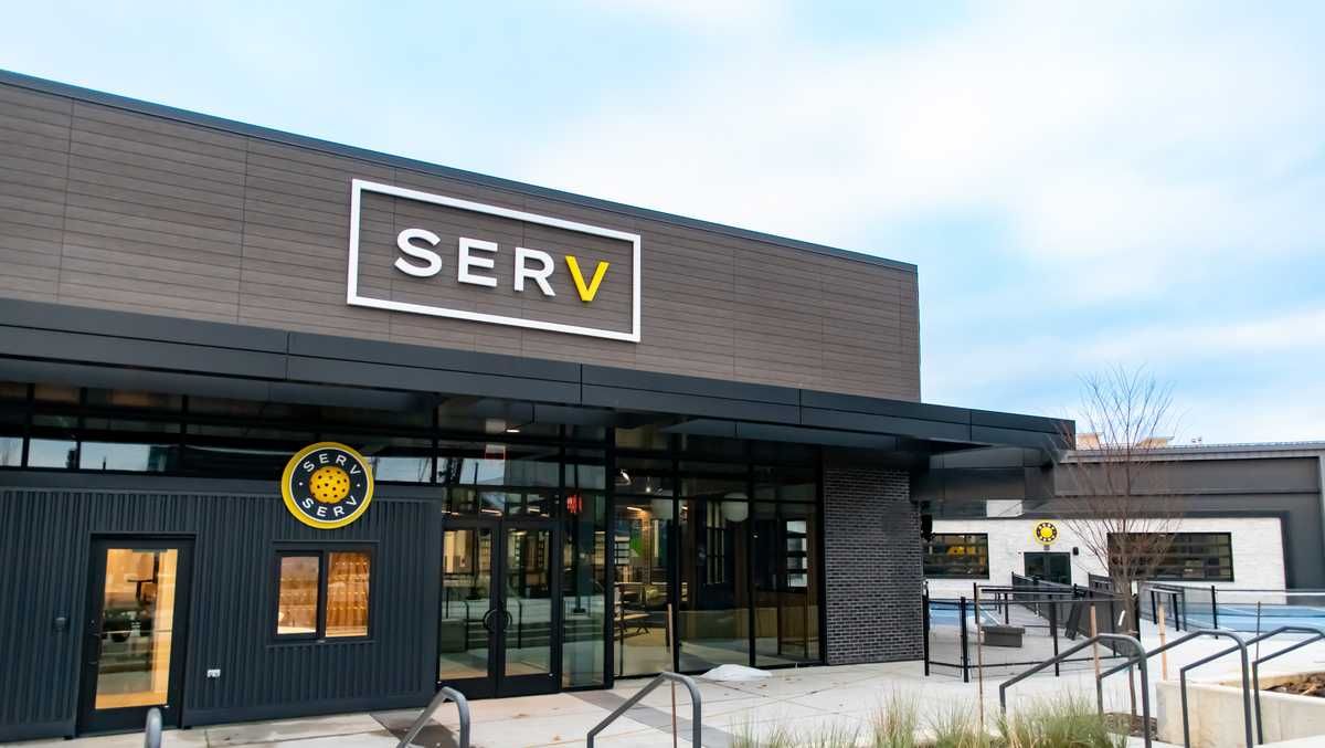 Modern building with a SERV sign, glass entrance, and snowy outdoor walkway.