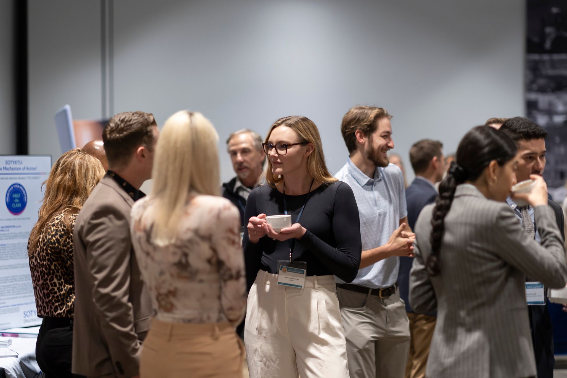 A group of people are standing in a room talking to each other.