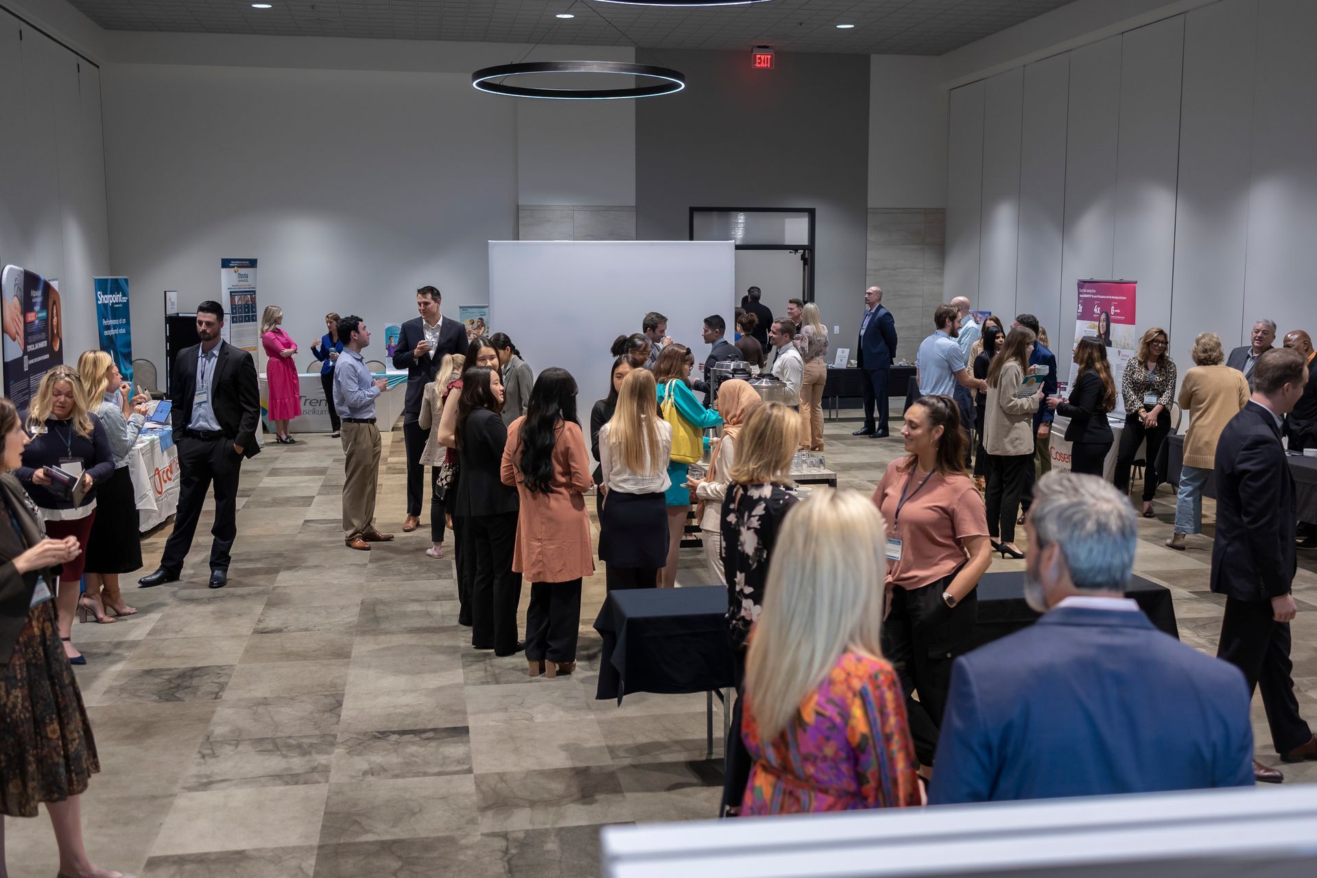 A group of people are standing in a large room talking to each other.