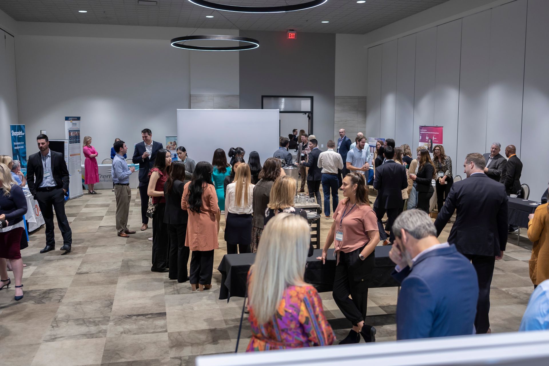A large group of people are standing in a room talking to each other.