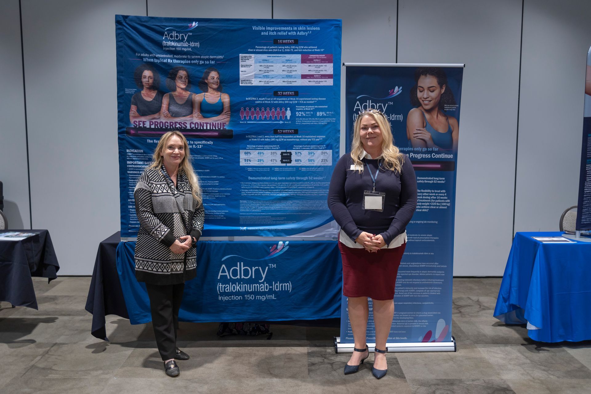 Two women are standing in front of a table with a banner that says adory student art