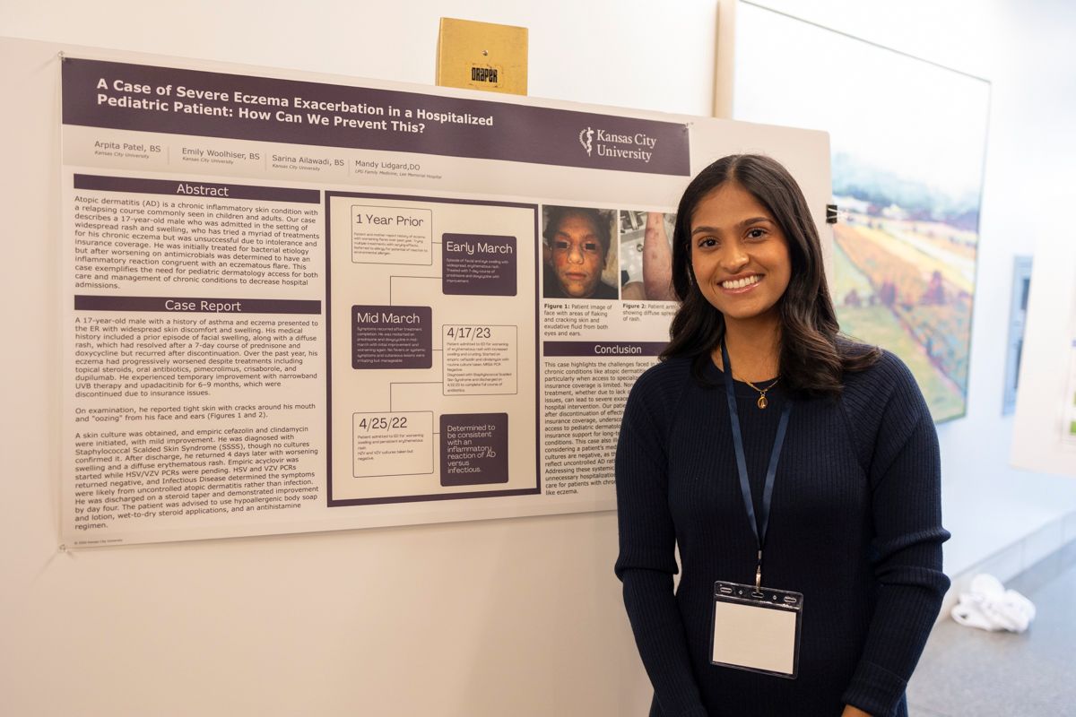 Woman stands in front of her poster presentation at KSDDS Annual Conference