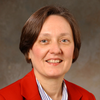 A woman wearing a red jacket and striped shirt smiles for the camera