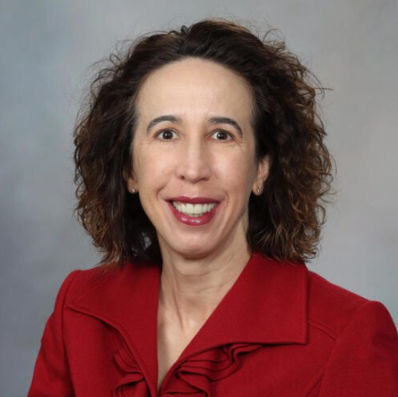 A woman in a red jacket is smiling for the camera.