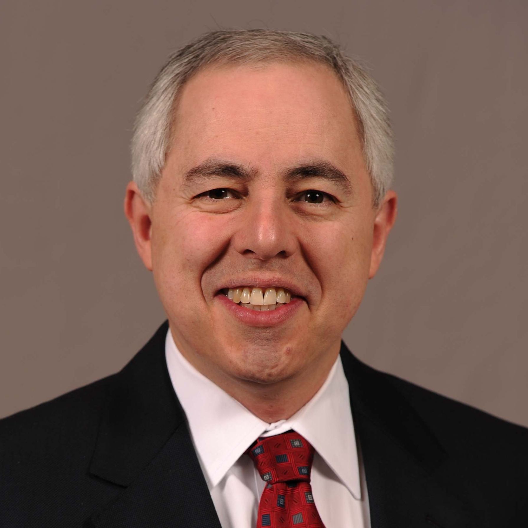 A man in a suit and tie is smiling for the camera