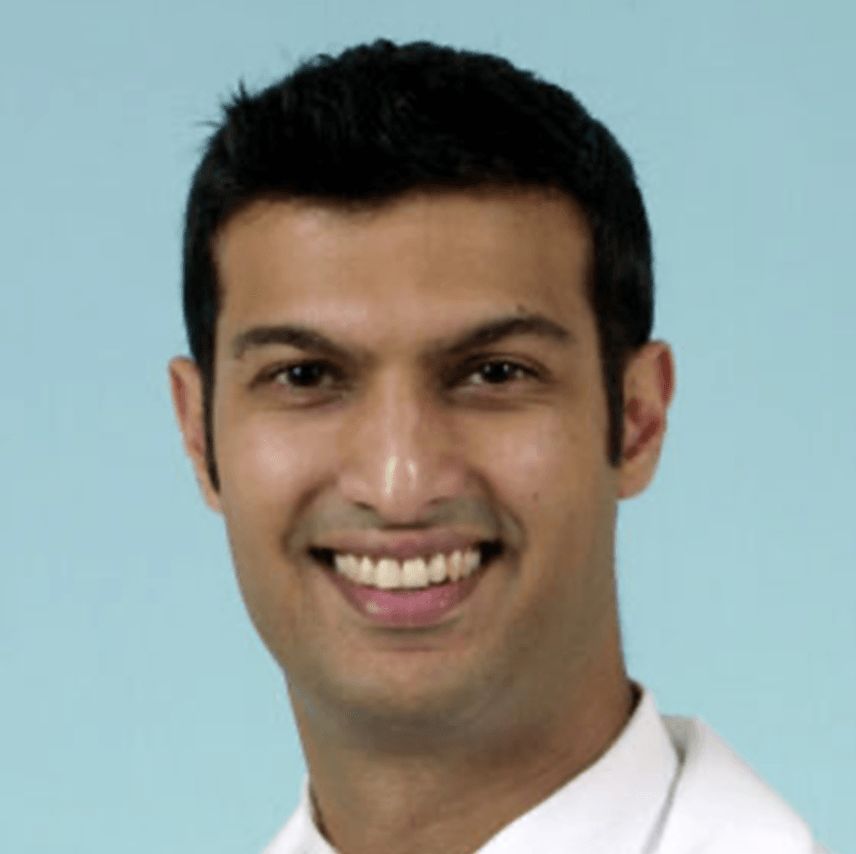 A man in a white shirt is smiling for the camera