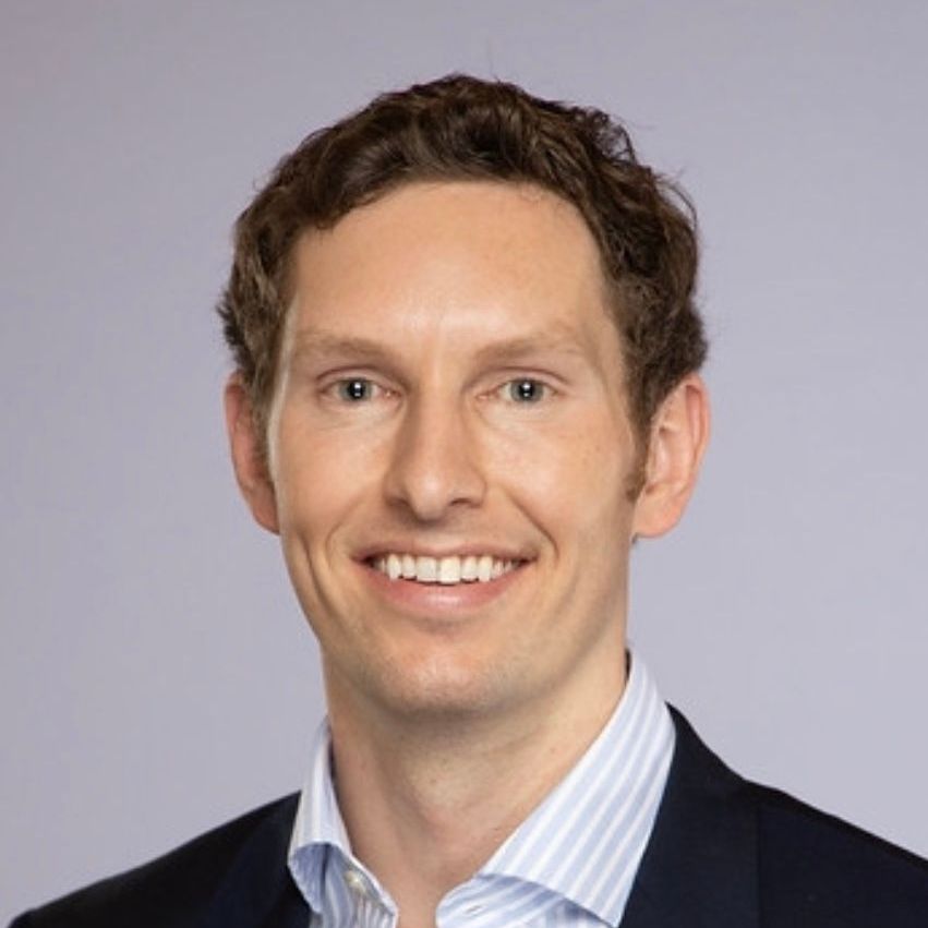 A man in a suit and striped shirt is smiling for the camera.