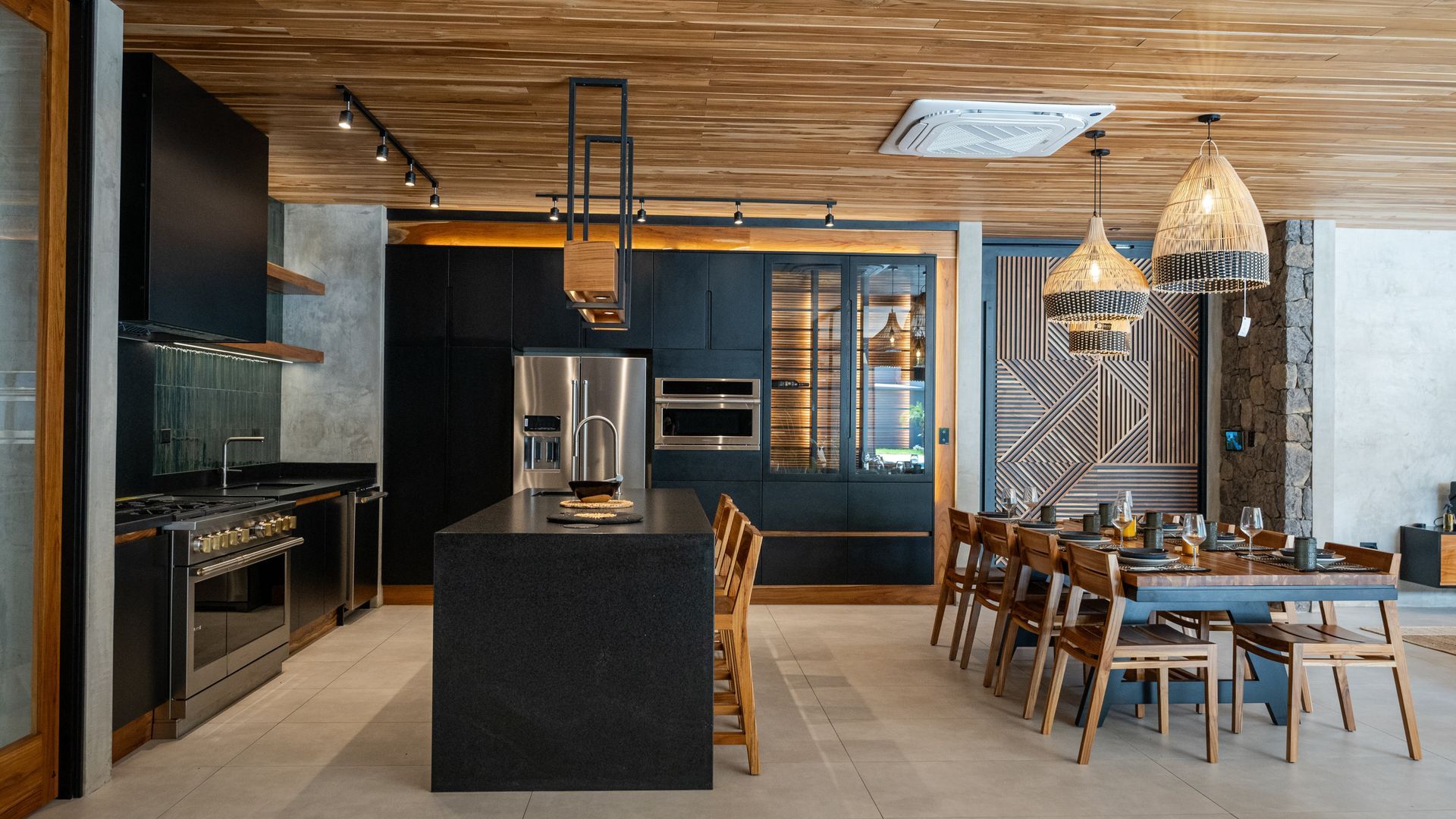 Modern kitchen with dark cabinetry, stainless steel appliances, and a wood ceiling; dining table set.