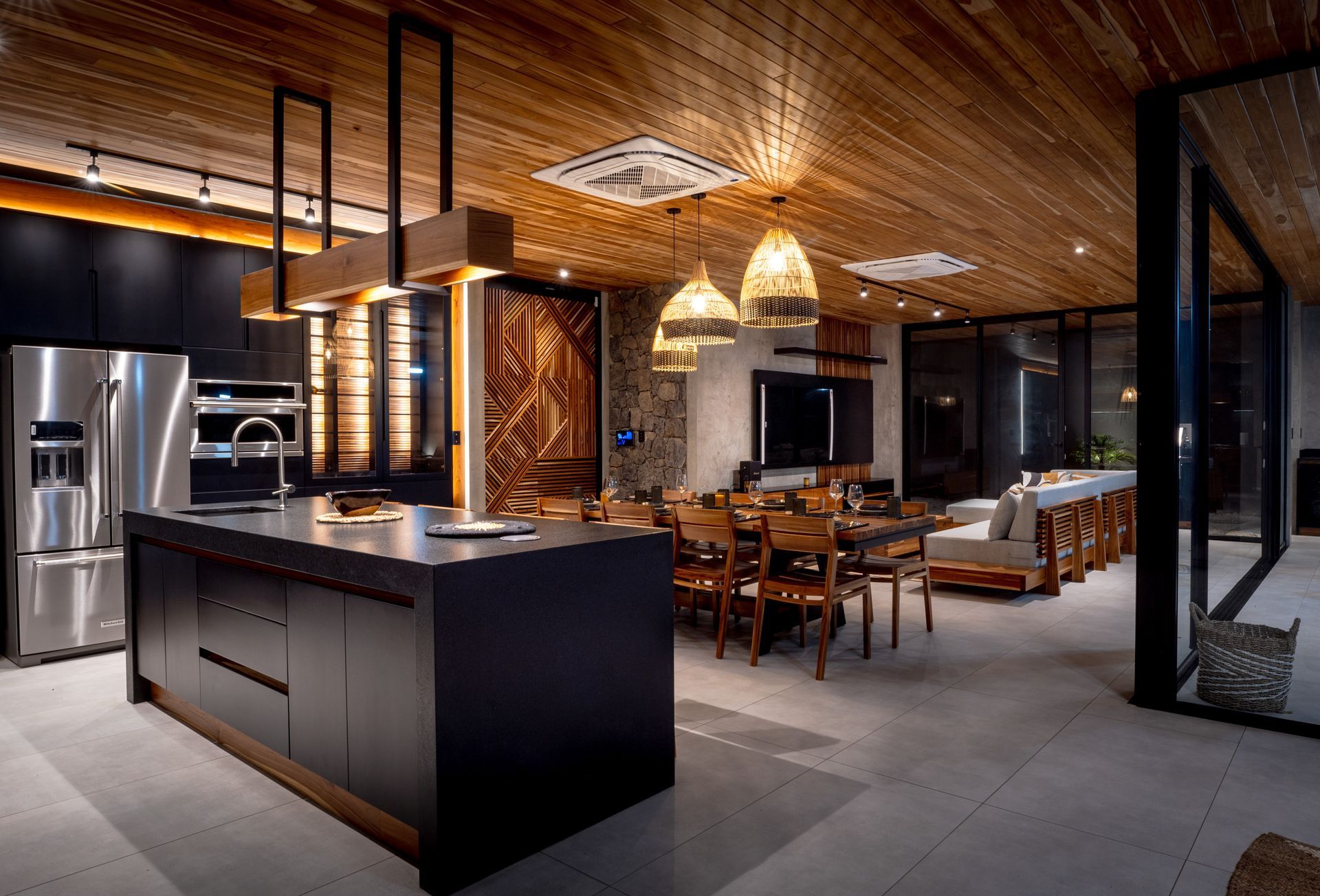 Modern kitchen and dining area with dark cabinetry, stainless steel appliances, and a wood ceiling.
