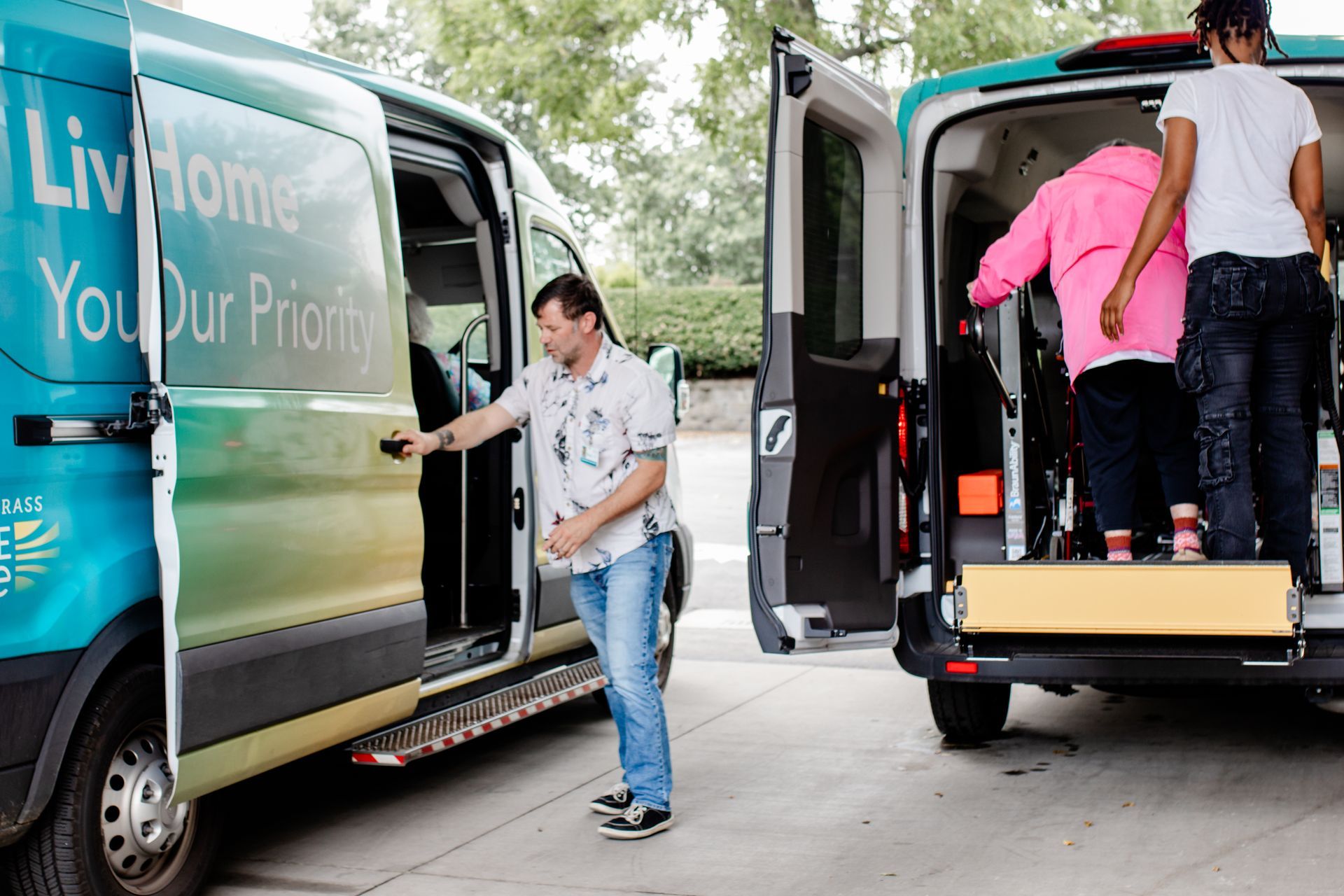 PACE worker assists a participant into a transport van while another person opens the van door.

