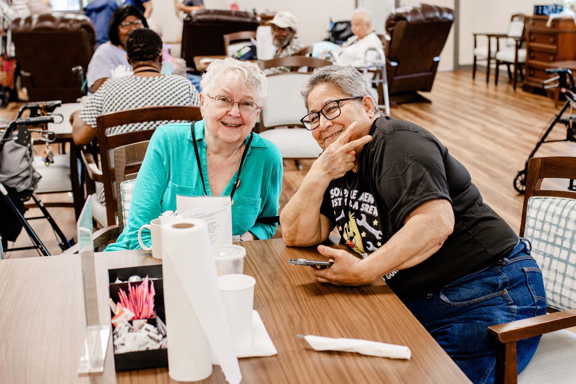 Two female PACE participants smiling and socializing in the day room of the Bluegrass PACE Center.
