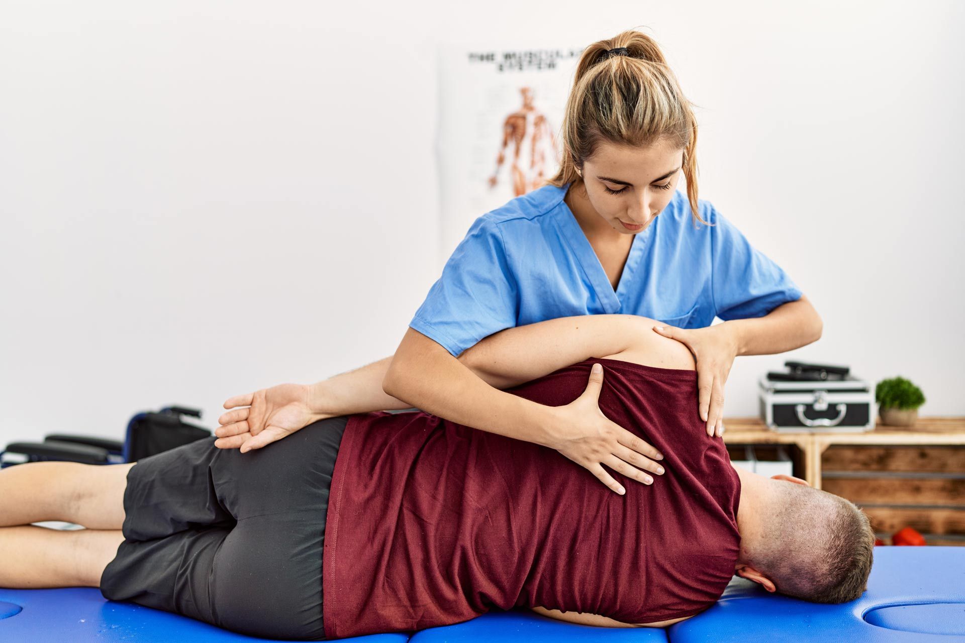 Young-hispanic-physioterapist-woman-make-back-rehab-treatment-to-man-at-the-clinic