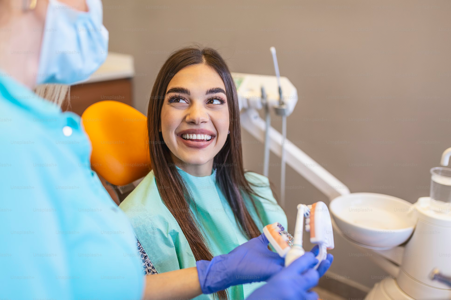 Patient smiling in a dental chair as a dentist prepares a treatment with tools nearby