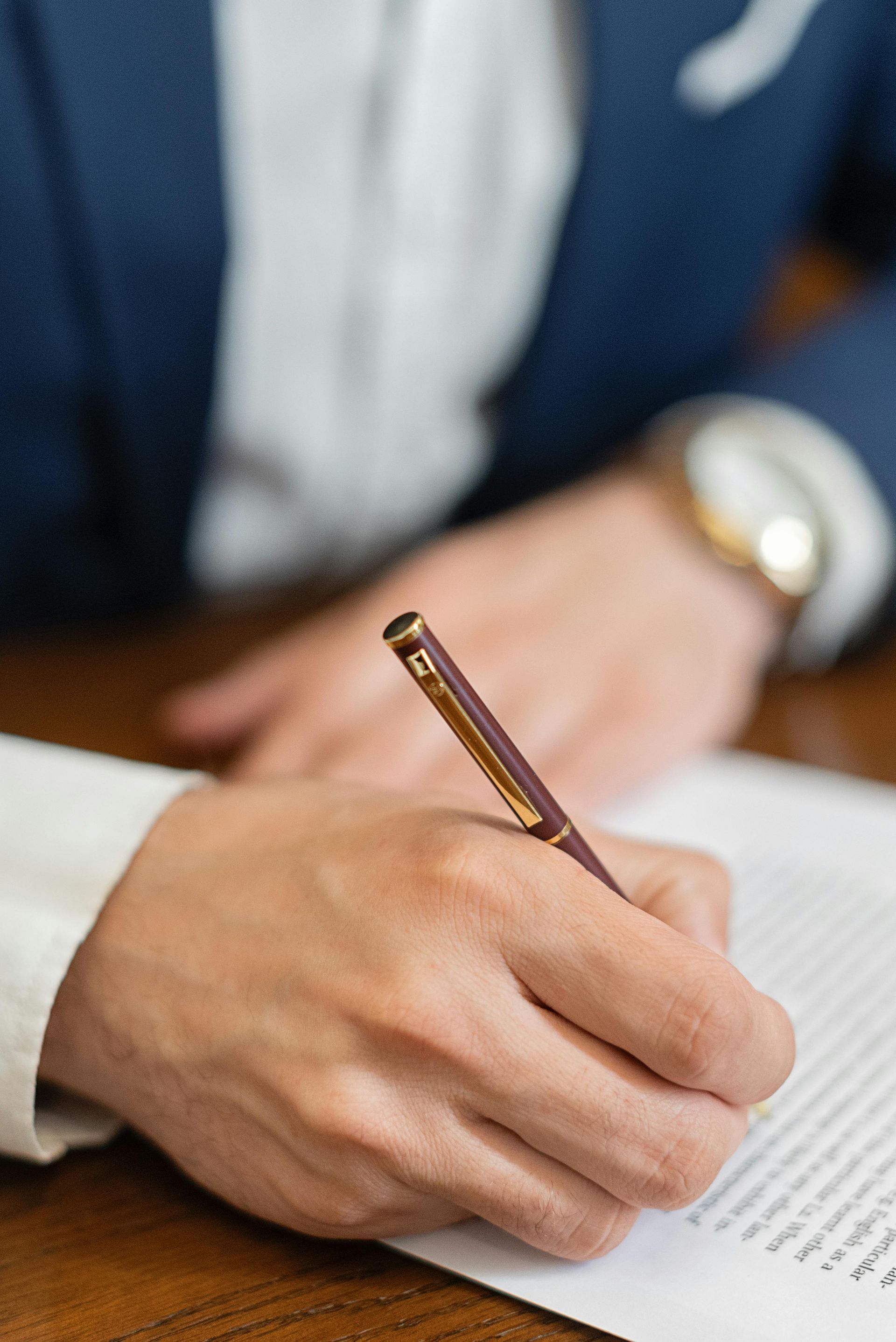 A person is writing on a piece of paper with a pen.