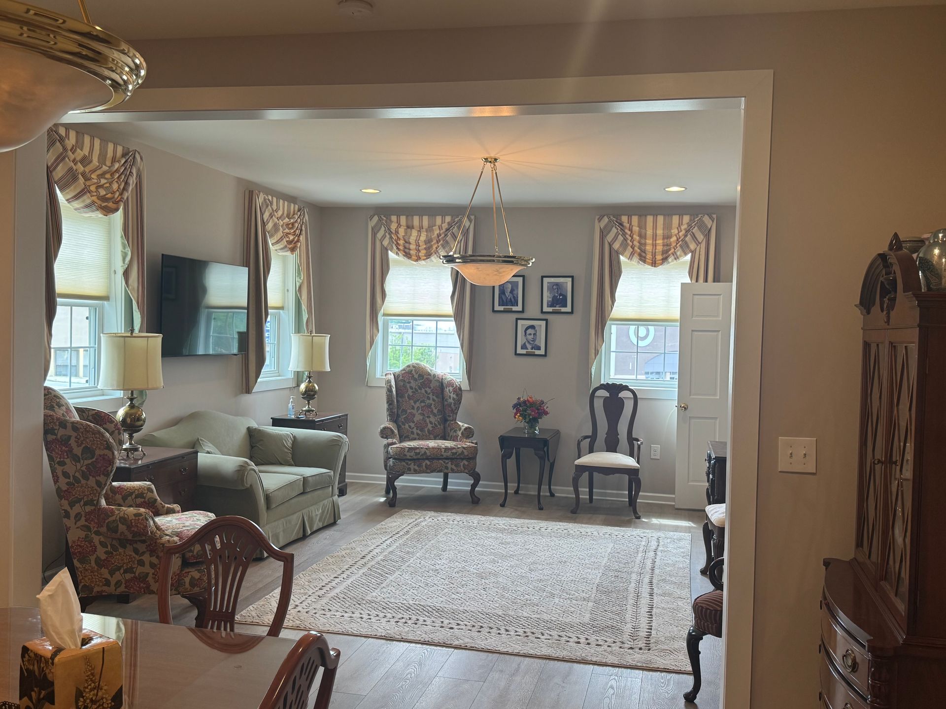 Elegant living room with patterned chairs, chandelier, and large windows with drapes