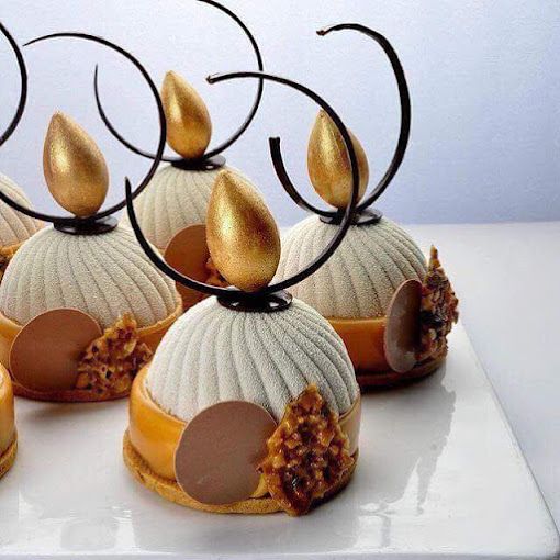 Une assiette blanche surmontée de trois desserts aux décorations dorées.