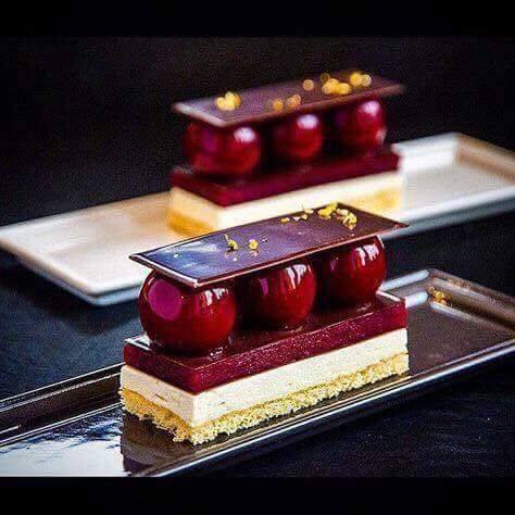 Un gros plan d'un dessert avec des cerises dessus sur une assiette.