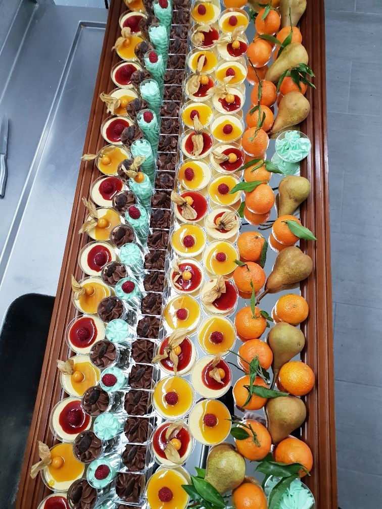 Une longue table en bois surmontée d'une variété de desserts et de fruits.