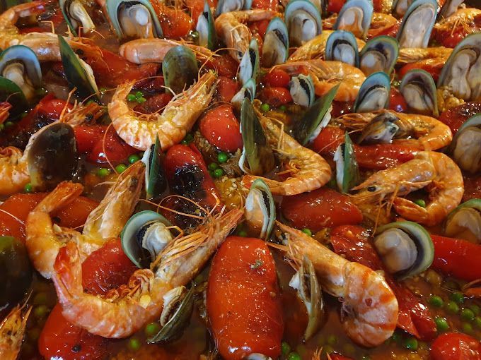 Une paella aux crevettes, moules, tomates et petits pois