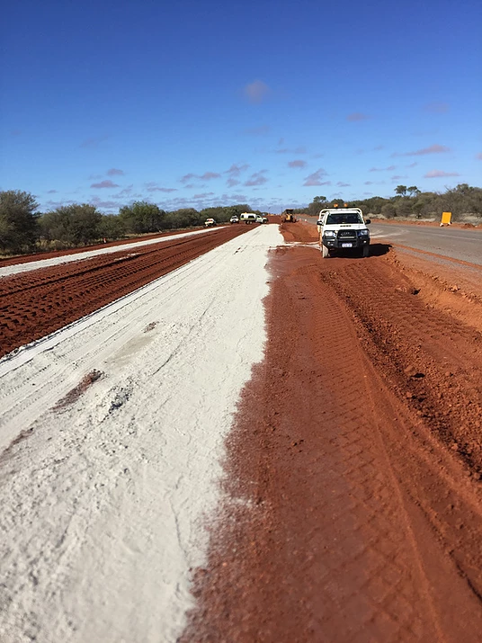 A white use driving down a dirt road.