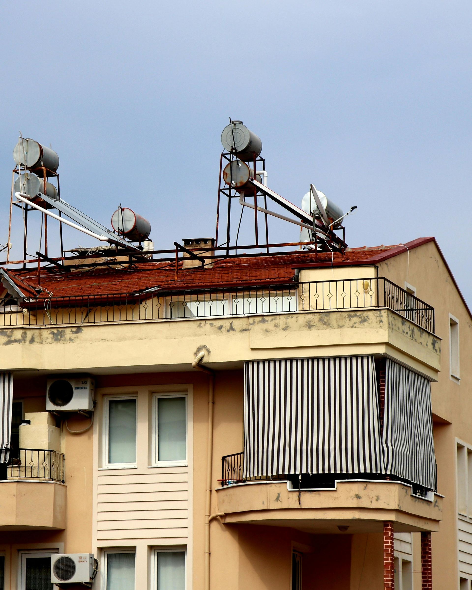 Apartment building with rooftop satellite dishes and air conditioners under a blue sky