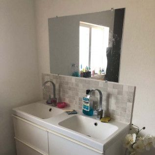 Bathroom vanity with double sink, mirror, and toiletries on the counter