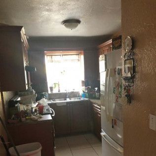 Small kitchen with brown cabinets, white refrigerator, and bright window over the sink.