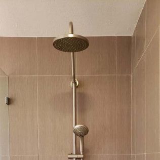 Bathroom shower with bronze fixtures and beige tiled wall
