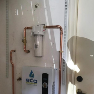 White utility cabinet with copper pipes and a water filter system inside