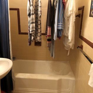 Bathroom shower-tub with clothes hanging across the rod and a sink at left