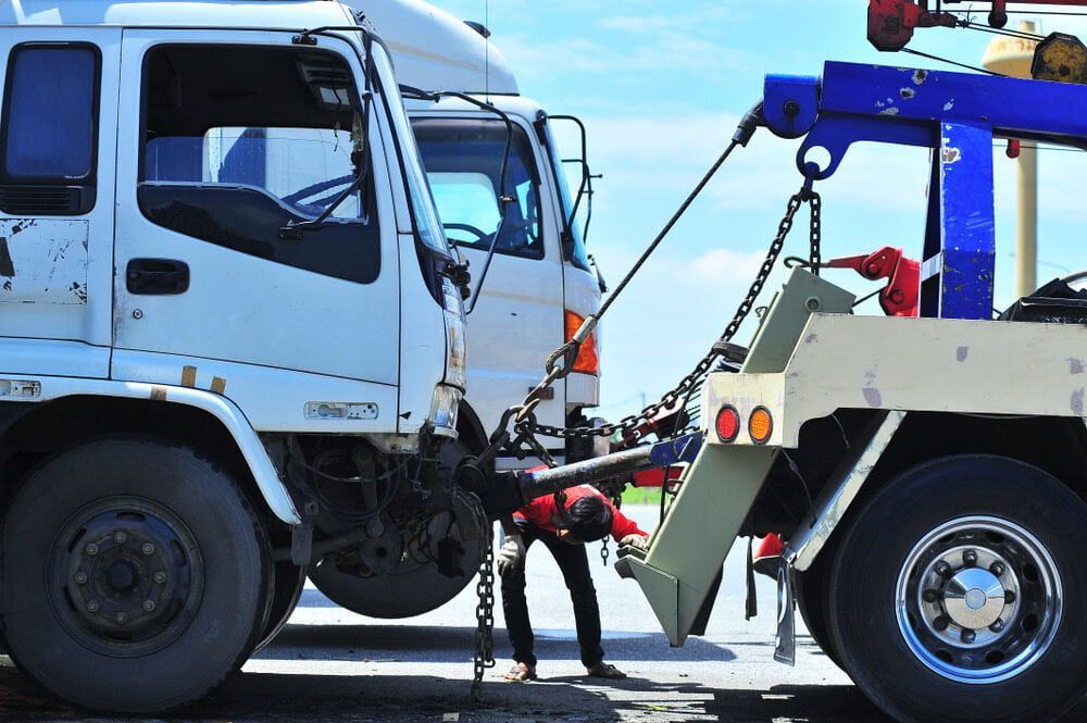 A Tow Truck Is Towing a Truck that Has Been Damaged in An Accident — Coast Mechanical Services In Berkeley Vale, NSW