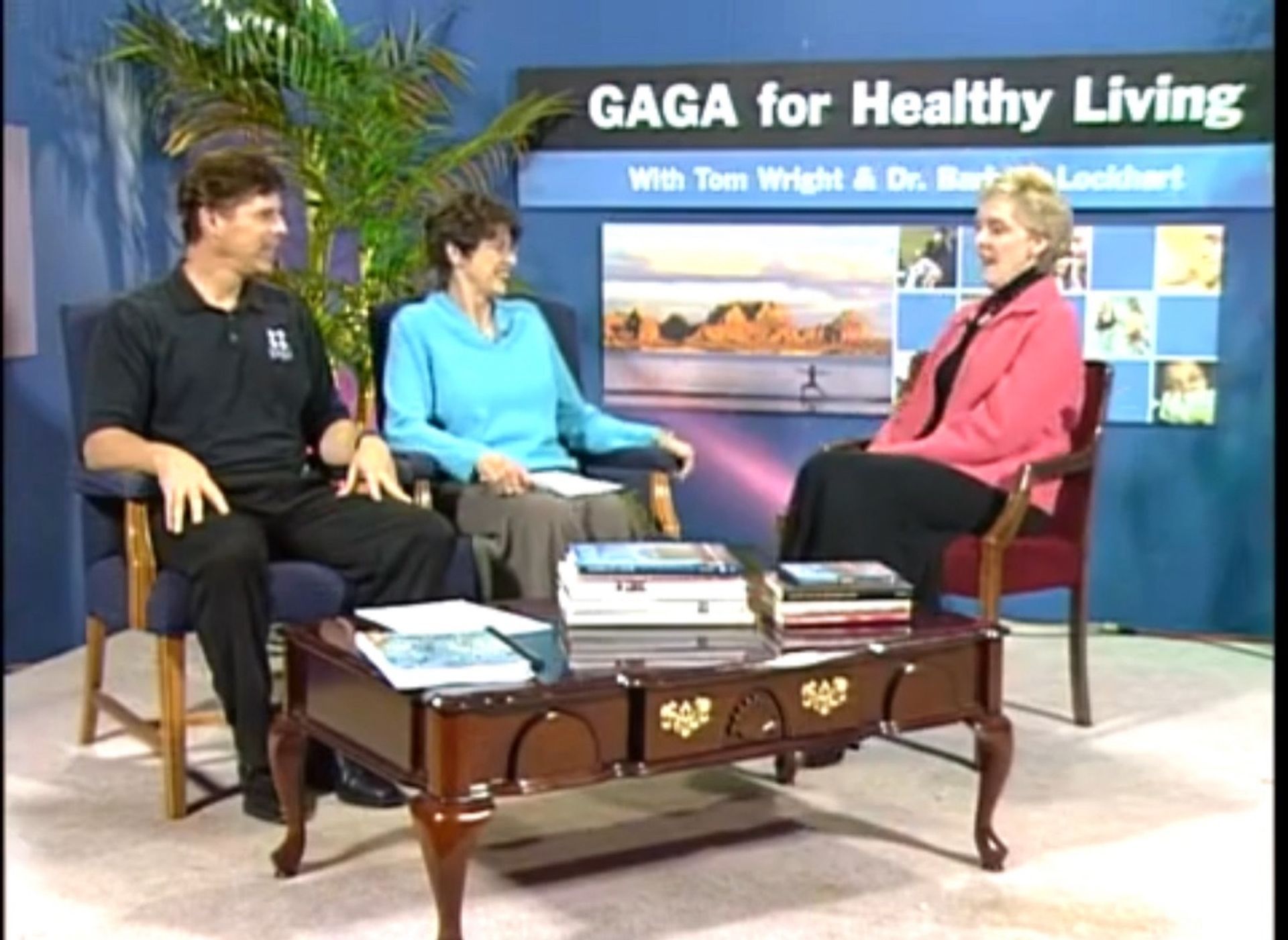 Tom Wright and two women sit at a table in front of a sign that says gaga for healthy living