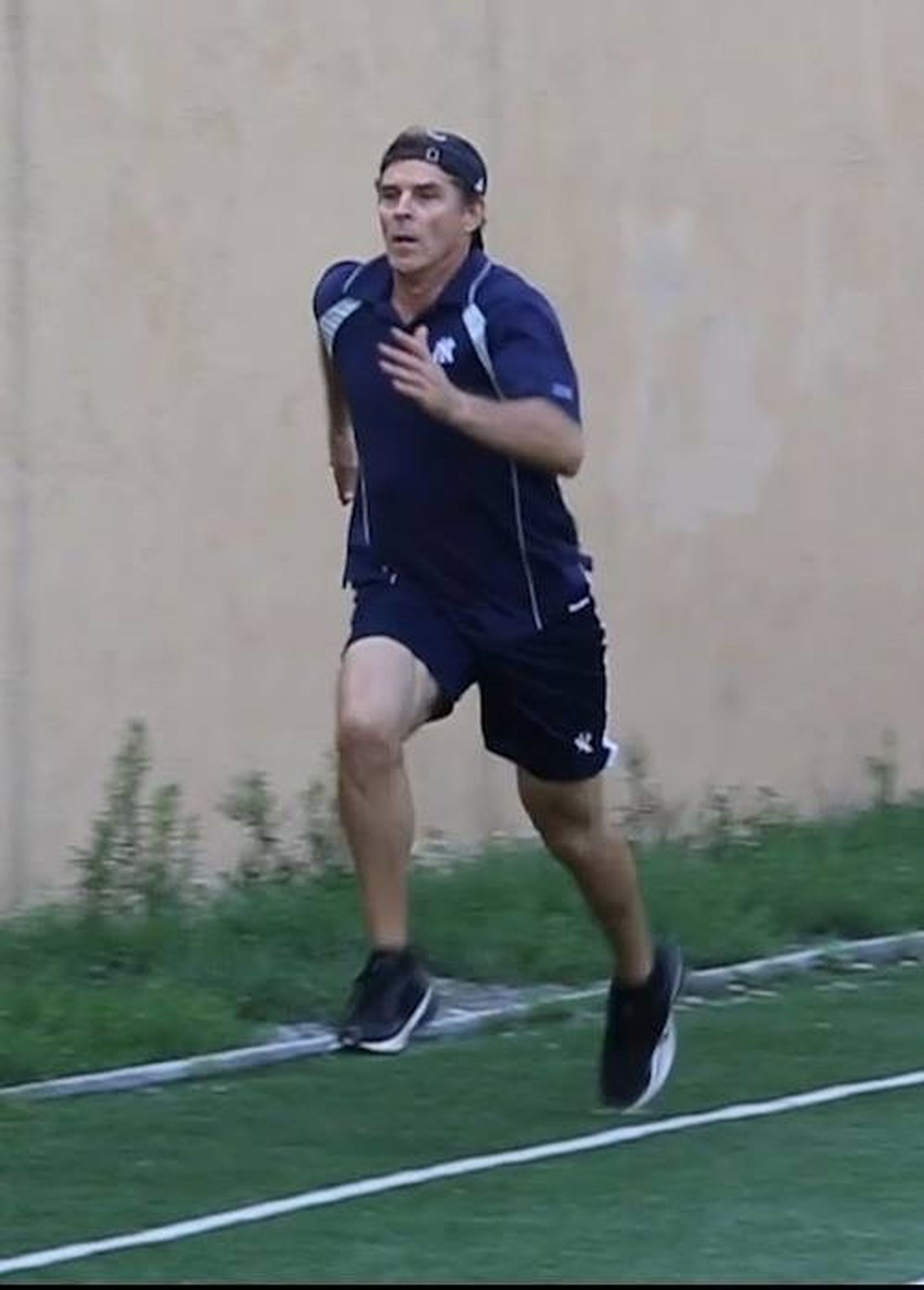 Tom Wright in a blue shirt and shorts is running on a track