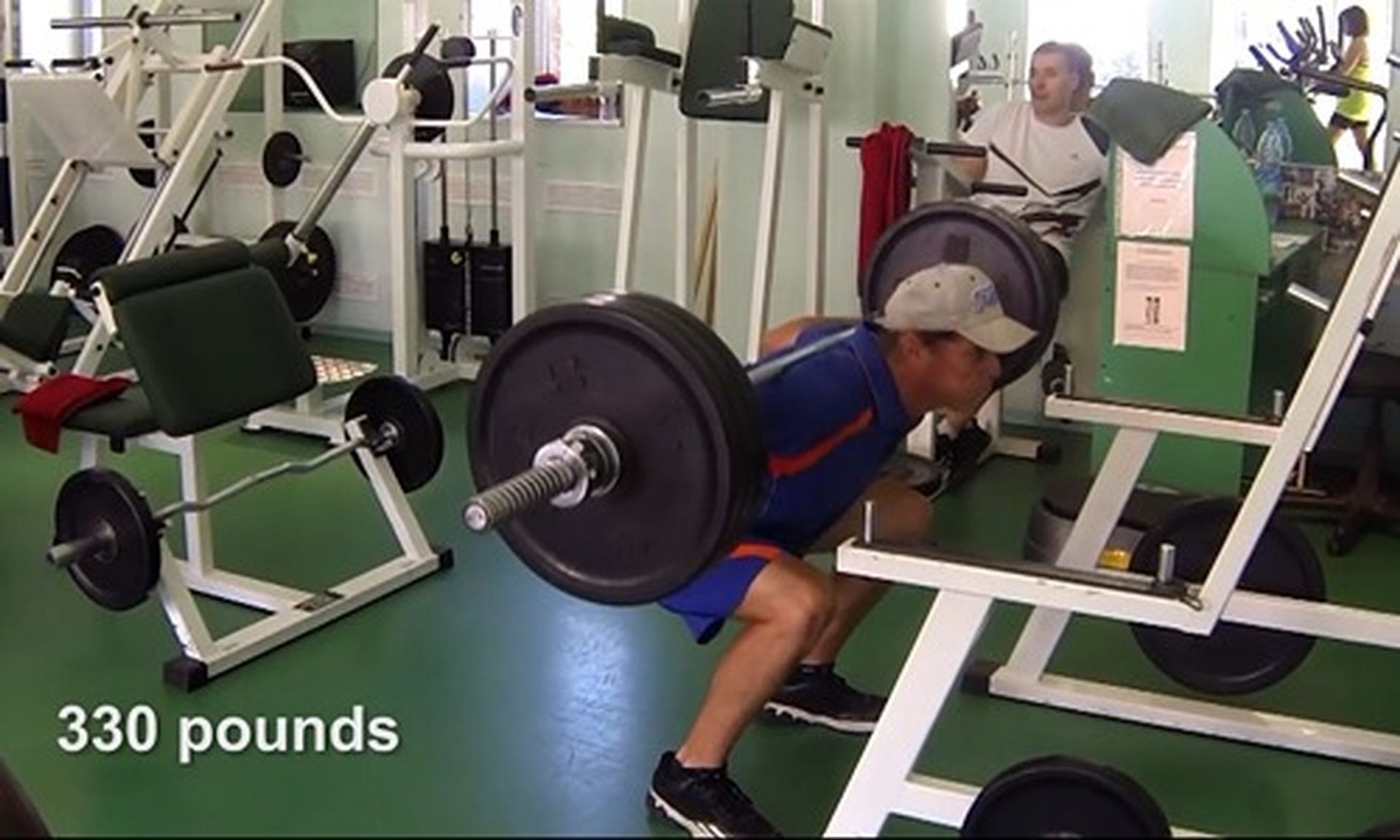 Tom Wright squatting with a barbell in a gym that says 330 pounds