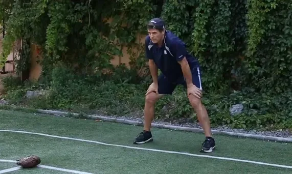 Tom Wright is standing on a soccer field with his hands on his knees.