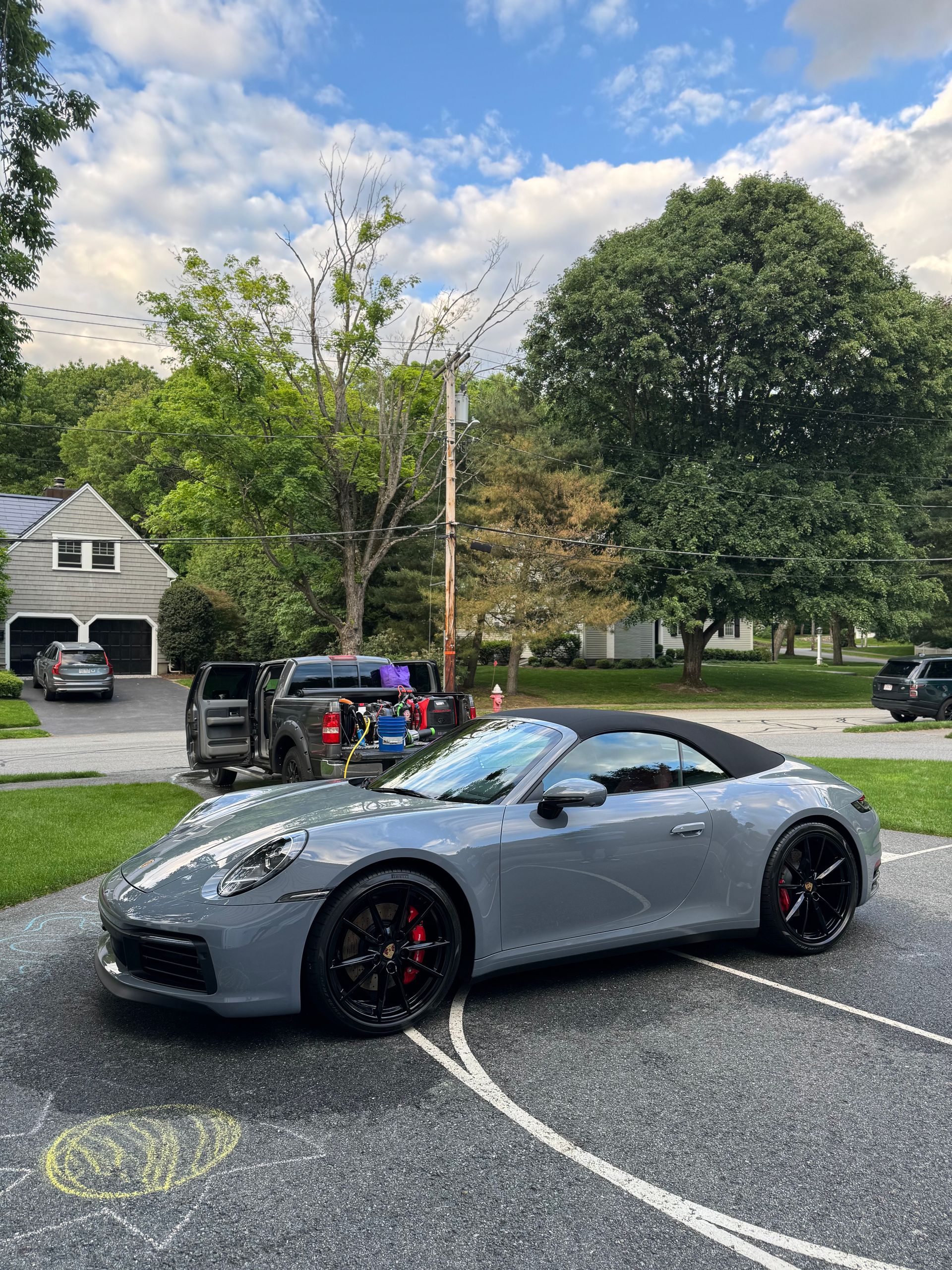 Gray sports car parked on a suburban street under a cloudy sky