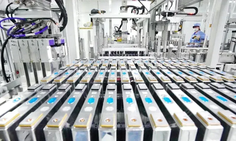 Linea di produzione automatizzata con file di pacchi batteria e macchinari robotici in alto
