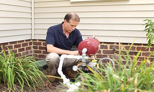 A Man Is Working On A Water Pump Outside Of A House - Oklahoma City, OK - Total Pump & Supply