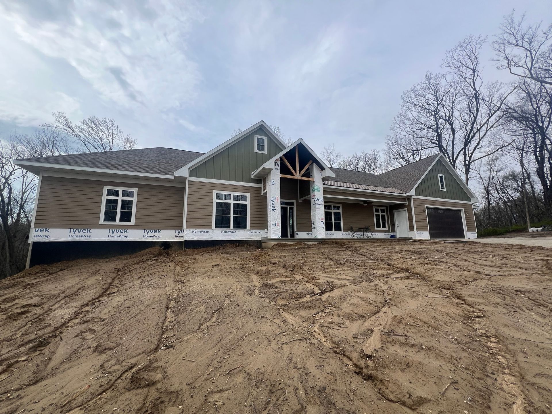 A large house is being built in the middle of a dirt field.