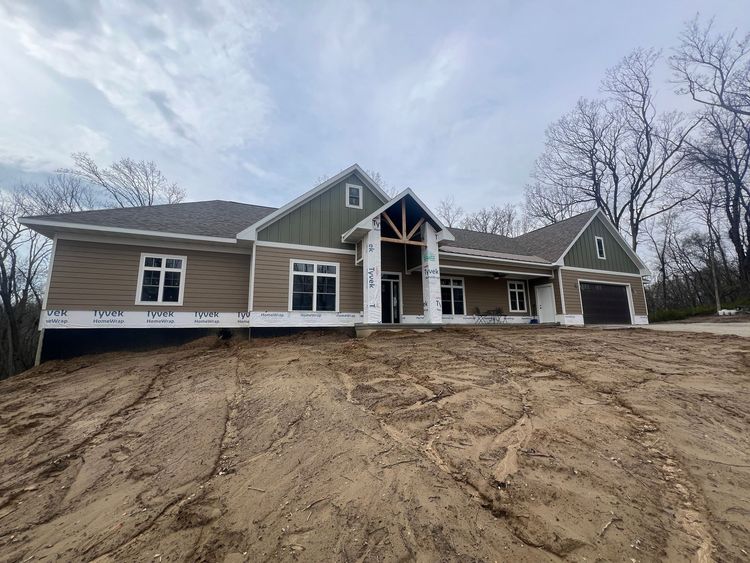 A large house is being built on top of a dirt hill.