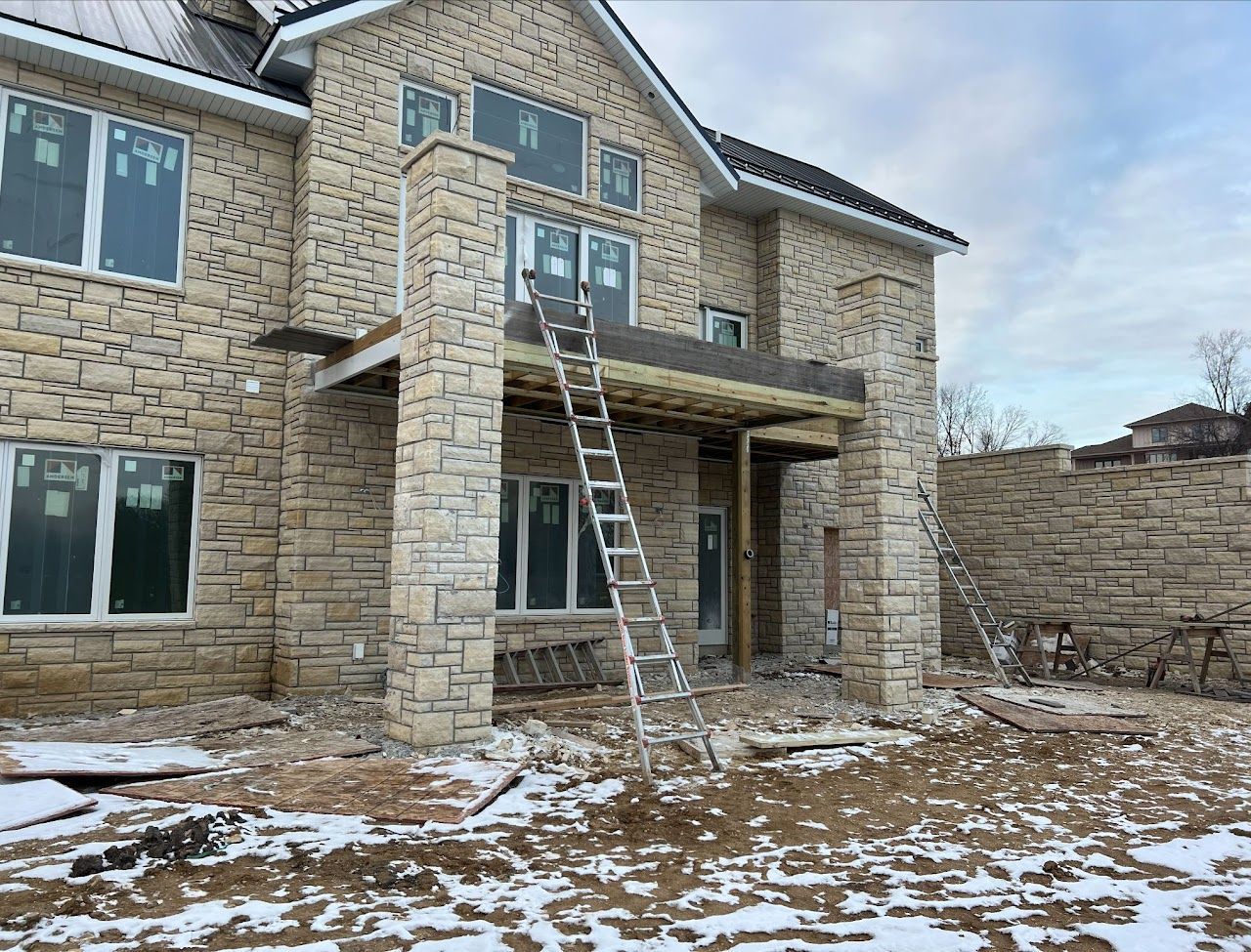 A large brick house under construction with a ladder in front of it.
