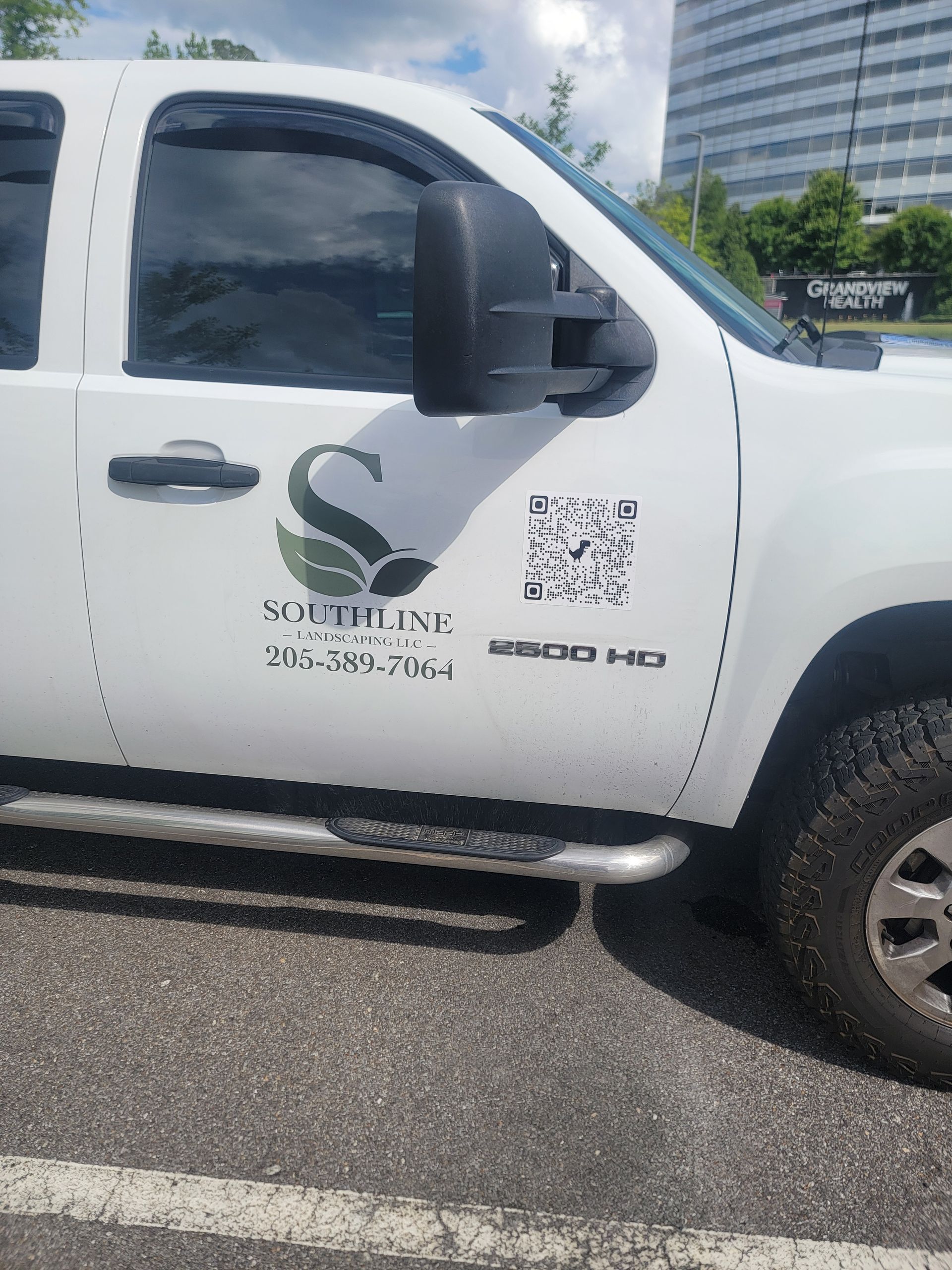 White pickup truck with company logo and phone number parked in a lot, side view