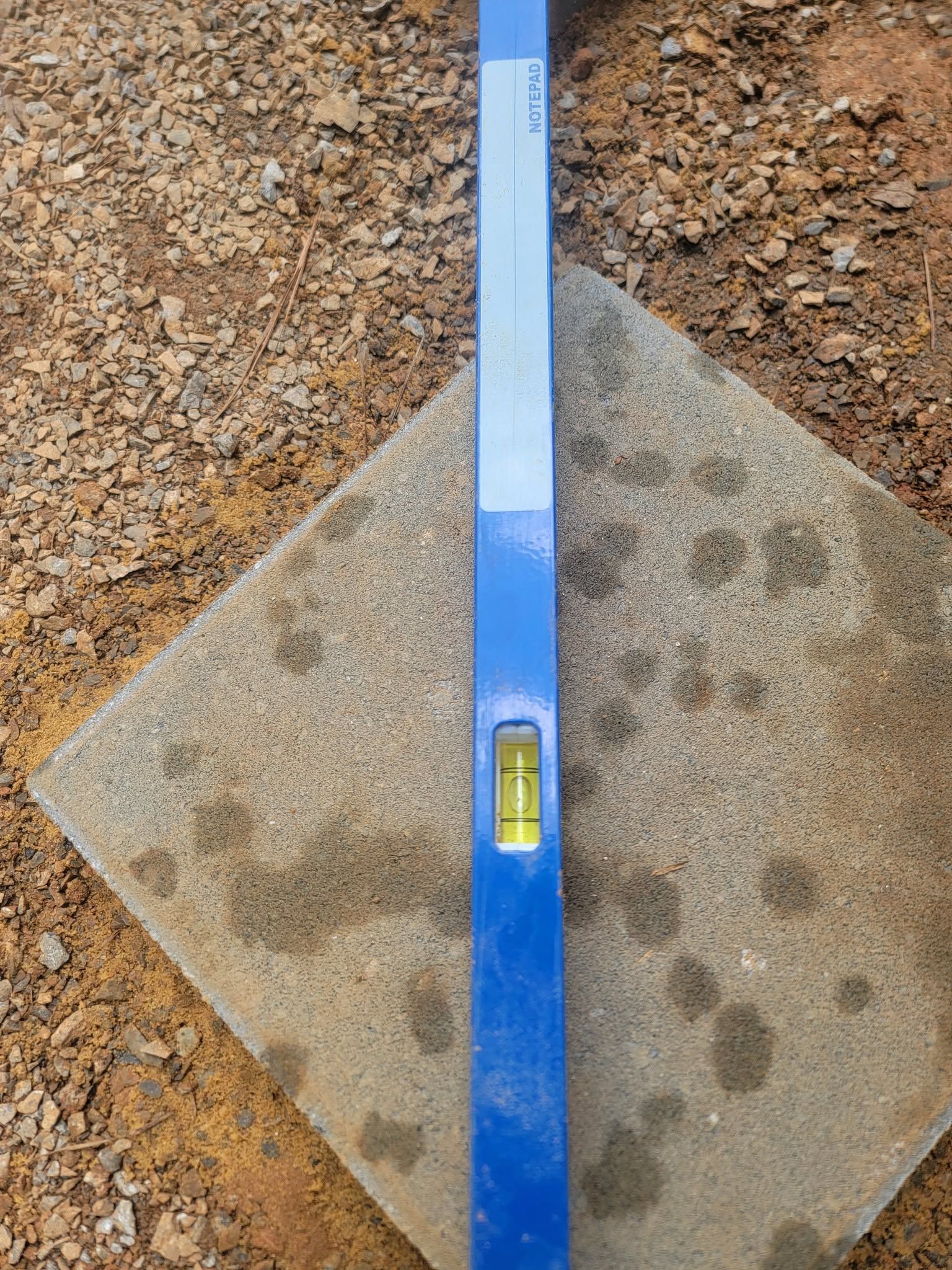 Blue spirit level centered on a sandy surface with a visible bubble gauge
