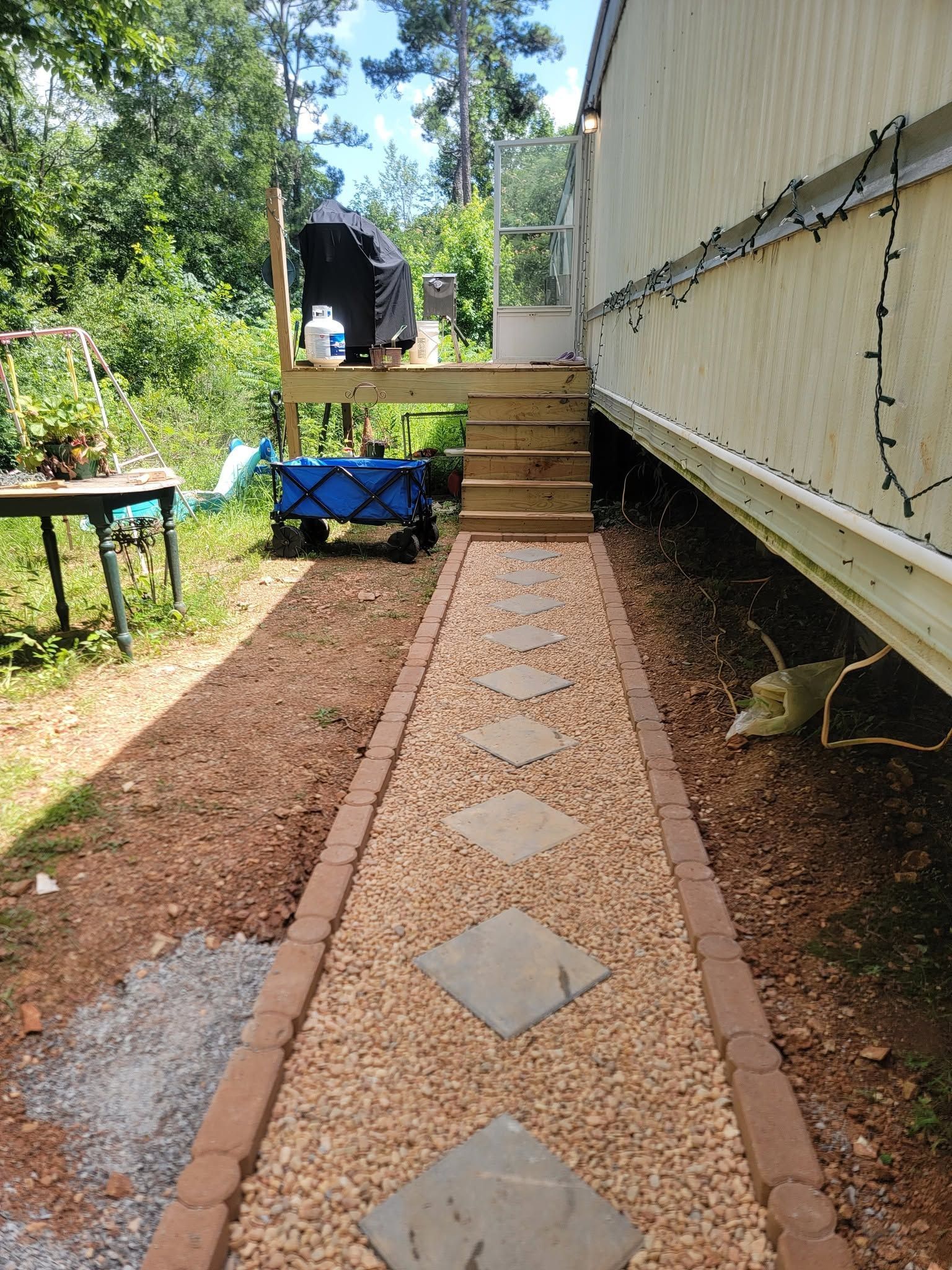Gravel walkway with brick edging and stepping stones leading to steps beside a house