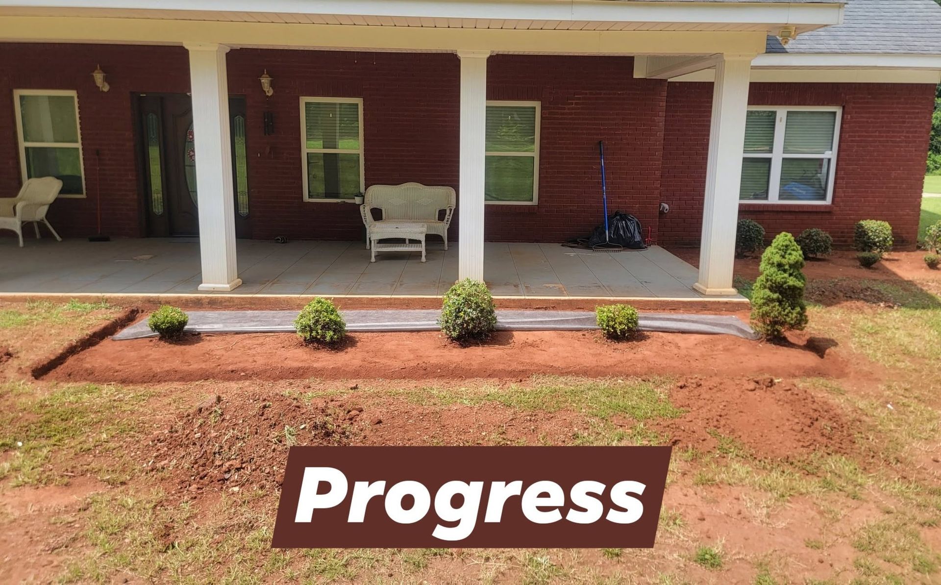 Front porch with red brick walls, white columns, and small shrubs in a landscaped yard; “Progress” label at bottom