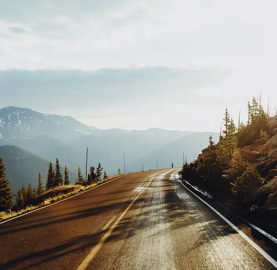 A car is driving down a road with mountains in the background